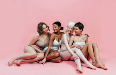 Farklı tür ten rengine sahip çok ırklı bir grup kadın stüdyoda birlikte poz veriyor. Vücut pozitifliği ve kendini kabullenme kavramı