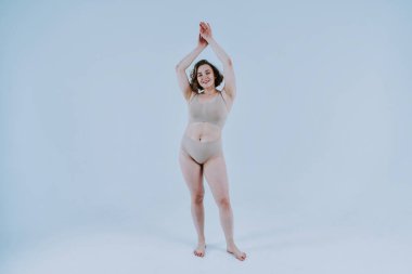 Stüdyoda iç çamaşırı giyen güzel bir kadının görüntüsü. Vücut pozitifliği ve kendini kabullenme kavramı