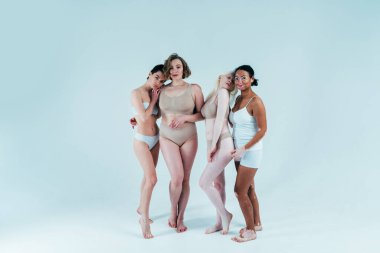 Farklı tür ten rengine sahip çok ırklı bir grup kadın stüdyoda birlikte poz veriyor. Vücut pozitifliği ve kendini kabullenme kavramı