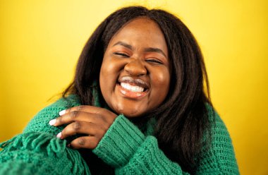 Sarı arka planda günlük kıyafetlerle poz veren güzel bir kadın.