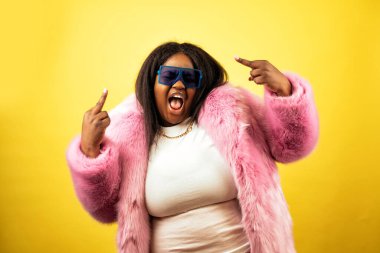 Sarı arka planda kürklü poz veren güzel bir kadın.