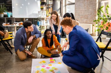 Proje yöneticileri ve çalışanları fikir üretmek için beyin fırtınası yapıyorlar - çok ırklı işçi grubu yeni açılan bir ofiste iş toplantısı yapıyor