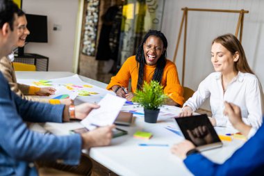 Proje yöneticileri ve çalışanları fikir üretmek için beyin fırtınası yapıyorlar - çok ırklı işçi grubu yeni açılan bir ofiste iş toplantısı yapıyor