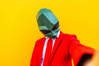3 boyutlu origami maskeli havalı bir adam şık renkli kıyafetler giyiyor. Reklamcılık için yaratıcı bir konsept, renkli arka planda komik şeyler yapan hayvan kafası maskesi.