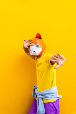 3 boyutlu origami maskeli havalı bir adam şık renkli kıyafetler giyiyor. Reklamcılık için yaratıcı bir konsept, renkli arka planda komik şeyler yapan hayvan kafası maskesi.