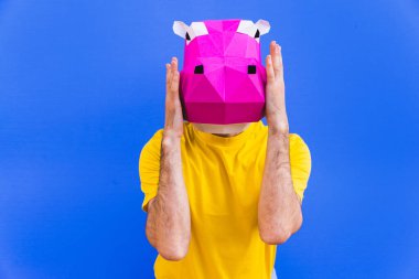 3 boyutlu origami maskeli havalı bir adam şık renkli kıyafetler giyiyor. Reklamcılık için yaratıcı bir konsept, renkli arka planda komik şeyler yapan hayvan kafası maskesi.