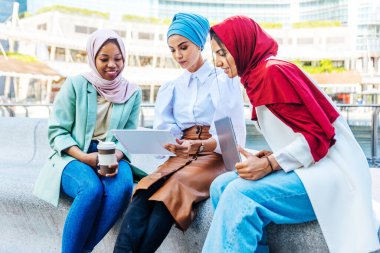 Çok ırklı Müslüman kızlar günlük kıyafetler giyip, geleneksel tesettüre girip dışarıda eğleniyorlar. 3 Arap genç kız.