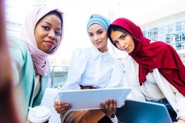 Çok ırklı Müslüman kızlar günlük kıyafetler giyip, geleneksel tesettüre girip dışarıda eğleniyorlar. 3 Arap genç kız.