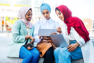 Çok ırklı Müslüman kızlar günlük kıyafetler giyip, geleneksel tesettüre girip dışarıda eğleniyorlar. 3 Arap genç kız.