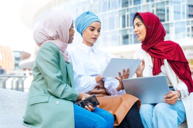 Çok ırklı Müslüman kızlar günlük kıyafetler giyip, geleneksel tesettüre girip dışarıda eğleniyorlar. 3 Arap genç kız.