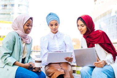 Çok ırklı Müslüman kızlar günlük kıyafetler giyip, geleneksel tesettüre girip dışarıda eğleniyorlar. 3 Arap genç kız.