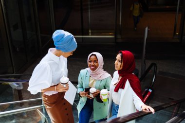 Çok ırklı Müslüman kızlar günlük kıyafetler giyip, geleneksel tesettüre girip dışarıda eğleniyorlar. 3 Arap genç kız.