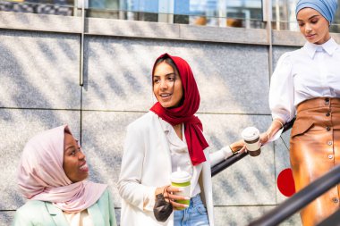 Çok ırklı Müslüman kızlar günlük kıyafetler giyip, geleneksel tesettüre girip dışarıda eğleniyorlar. 3 Arap genç kız.