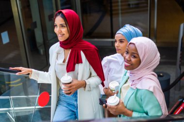Çok ırklı Müslüman kızlar günlük kıyafetler giyip, geleneksel tesettüre girip dışarıda eğleniyorlar. 3 Arap genç kız.
