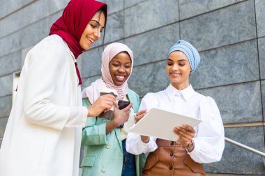 Çok ırklı Müslüman kızlar günlük kıyafetler giyip, geleneksel tesettüre girip dışarıda eğleniyorlar. 3 Arap genç kız.