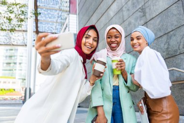 Çok ırklı Müslüman kızlar günlük kıyafetler giyip, geleneksel tesettüre girip dışarıda eğleniyorlar. 3 Arap genç kız.