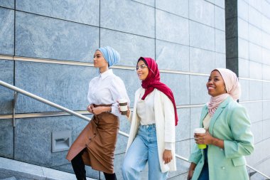 Çok ırklı Müslüman kızlar günlük kıyafetler giyip, geleneksel tesettüre girip dışarıda eğleniyorlar. 3 Arap genç kız.