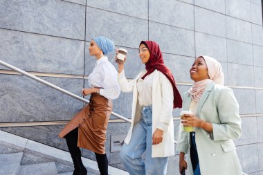 Çok ırklı Müslüman kızlar günlük kıyafetler giyip, geleneksel tesettüre girip dışarıda eğleniyorlar. 3 Arap genç kız.