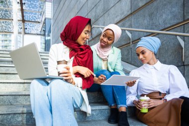 Çok ırklı Müslüman kızlar günlük kıyafetler giyip, geleneksel tesettüre girip dışarıda eğleniyorlar. 3 Arap genç kız.