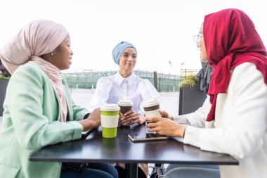 Çok ırklı Müslüman kızlar günlük kıyafetler giyip, geleneksel tesettüre girip dışarıda eğleniyorlar. 3 Arap genç kız.
