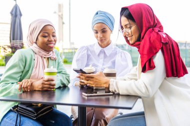 Çok ırklı Müslüman kızlar günlük kıyafetler giyip, geleneksel tesettüre girip dışarıda eğleniyorlar. 3 Arap genç kız.