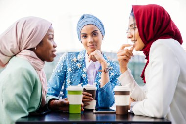 Çok ırklı Müslüman kızlar günlük kıyafetler giyip, geleneksel tesettüre girip dışarıda eğleniyorlar. 3 Arap genç kız.