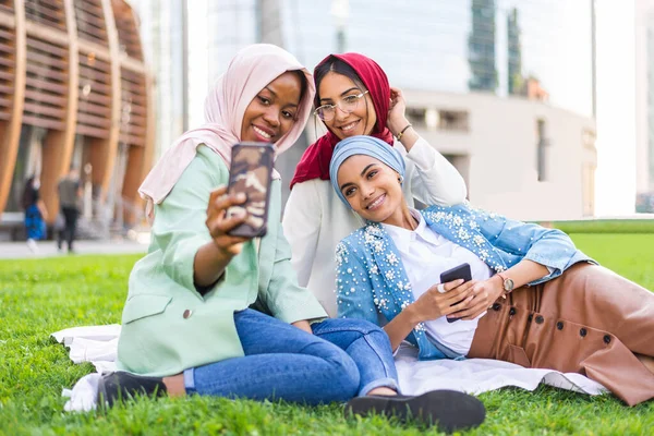 カジュアルな服と伝統的なヒジャーブのボンディングを身に着けているイスラム教徒の女の子の多民族グループと楽しい屋外で 3アラビア語の若い女の子 — ストック写真