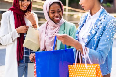 Çok ırklı Müslüman kızlar günlük kıyafetler giyip, geleneksel tesettüre girip dışarıda eğleniyorlar. 3 Arap genç kız.