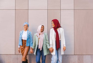 Çok ırklı Müslüman kızlar günlük kıyafetler giyip, geleneksel tesettüre girip dışarıda eğleniyorlar. 3 Arap genç kız.