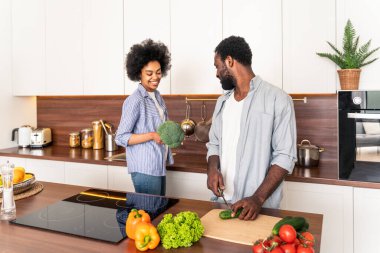Güzel Afro-Amerikan çifti evde yemek pişiriyor güzel ve neşeli siyah çift mutfakta birlikte yemek hazırlıyor.