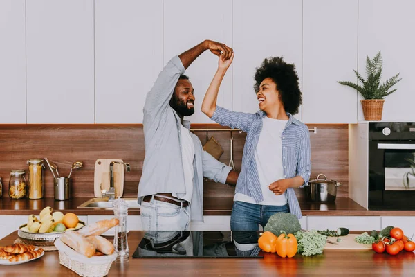 Beautiful afro american couple cooking at home - Beautiful and cheerful black couple preparing dinner together in the kitchen