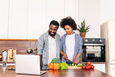 Güzel Afro-Amerikan çifti evde yemek pişiriyor güzel ve neşeli siyah çift mutfakta birlikte yemek hazırlıyor.