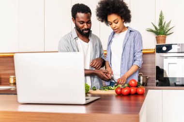 Güzel Afro-Amerikan çifti evde yemek pişiriyor güzel ve neşeli siyah çift mutfakta birlikte yemek hazırlıyor.