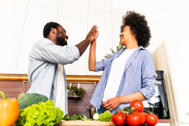 Güzel Afro-Amerikan çifti evde yemek pişiriyor güzel ve neşeli siyah çift mutfakta birlikte yemek hazırlıyor.