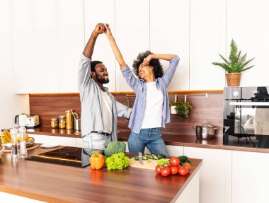 Güzel Afro-Amerikan çifti evde yemek pişiriyor güzel ve neşeli siyah çift mutfakta birlikte yemek hazırlıyor.