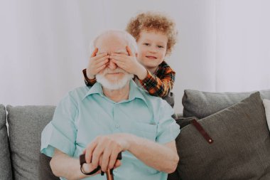 Büyükbaba ve torun evde oynuyorlar. Aile evde, büyükbaba yeğenine bakıyor.
