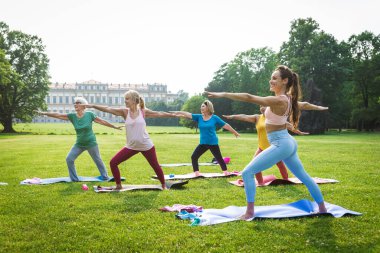 Parkta fitness eğitmeniyle eğitim gören çok ırklı yaşlı kadınlar grubu - aktif yaşlılar spor yapıyor.