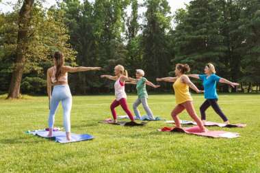 Parkta fitness eğitmeniyle eğitim gören çok ırklı yaşlı kadınlar grubu - aktif yaşlılar spor yapıyor.