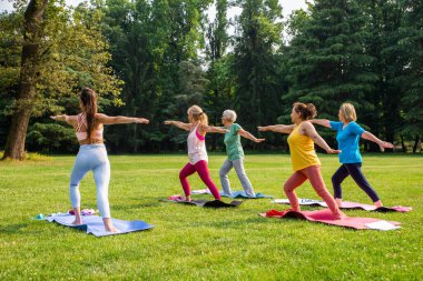 Parkta fitness eğitmeniyle eğitim gören çok ırklı yaşlı kadınlar grubu - aktif yaşlılar spor yapıyor.