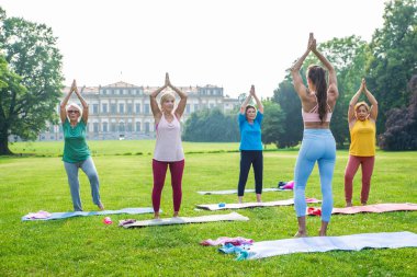 Parkta fitness eğitmeniyle eğitim gören çok ırklı yaşlı kadınlar grubu - aktif yaşlılar spor yapıyor.