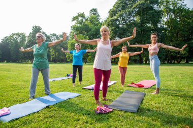 Parkta fitness eğitmeniyle eğitim gören çok ırklı yaşlı kadınlar grubu - aktif yaşlılar spor yapıyor.