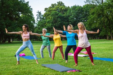 Parkta fitness eğitmeniyle eğitim gören çok ırklı yaşlı kadınlar grubu - aktif yaşlılar spor yapıyor.