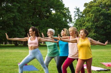 Parkta fitness eğitmeniyle eğitim gören çok ırklı yaşlı kadınlar grubu - aktif yaşlılar spor yapıyor.