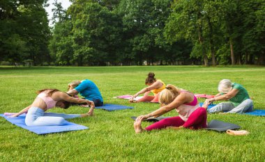 Parkta fitness eğitmeniyle eğitim gören çok ırklı yaşlı kadınlar grubu - aktif yaşlılar spor yapıyor.