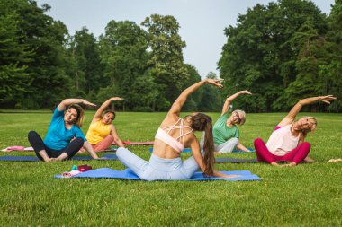 Parkta fitness eğitmeniyle eğitim gören çok ırklı yaşlı kadınlar grubu - aktif yaşlılar spor yapıyor.