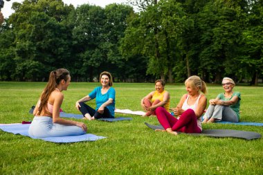 Parkta fitness eğitmeniyle eğitim gören çok ırklı yaşlı kadınlar grubu - aktif yaşlılar spor yapıyor.