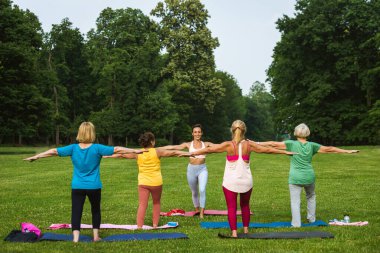 Parkta fitness eğitmeniyle eğitim gören çok ırklı yaşlı kadınlar grubu - aktif yaşlılar spor yapıyor.