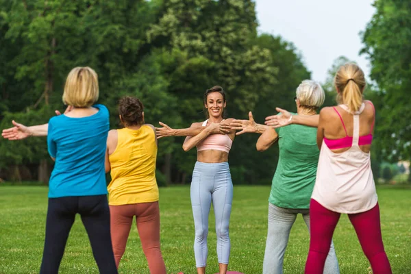 在公园接受健身教练训练的多族裔老年妇女群体 积极参加自然体育运动的老年人 — 图库照片