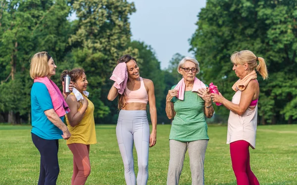 在公园接受健身教练训练的多族裔老年妇女群体 积极参加自然体育运动的老年人 — 图库照片