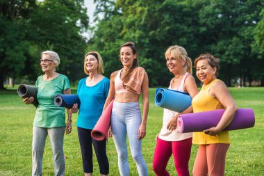 Parkta fitness eğitmeniyle eğitim gören çok ırklı yaşlı kadınlar grubu - aktif yaşlılar spor yapıyor.
